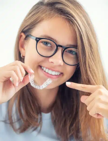 Woman smiling while holding Invisalign clear aligners