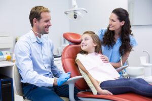 Orthodontist speaking with a parent and child about interceptive orthodontics during a dental visit