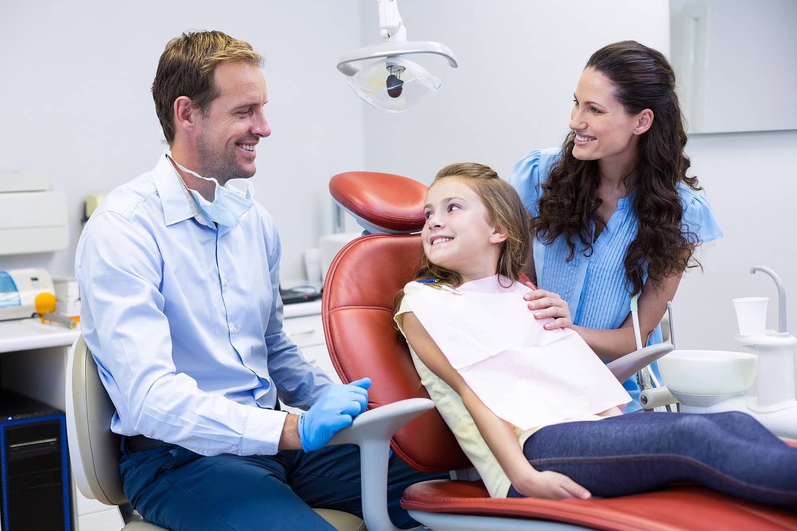 Orthodontist speaking with a parent and child about interceptive orthodontics during a dental visit